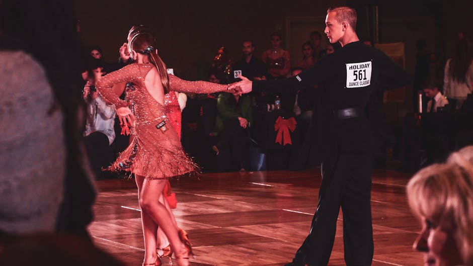 A couple performs a graceful ballroom dance routine on stage during a lively competition event.