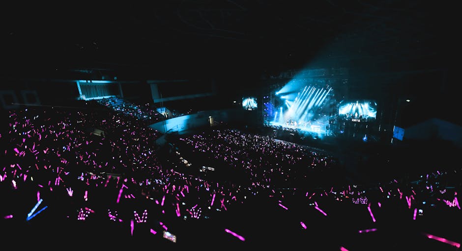 Exciting live concert with a massive audience and colorful light sticks creating vibrant energy.